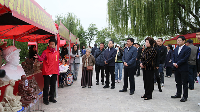 图为残疾非遗传承人介绍泥塑作品