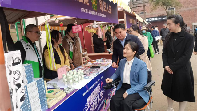 图为周蓉观摩爱心助残集市 图为周蓉观摩爱心助残集市